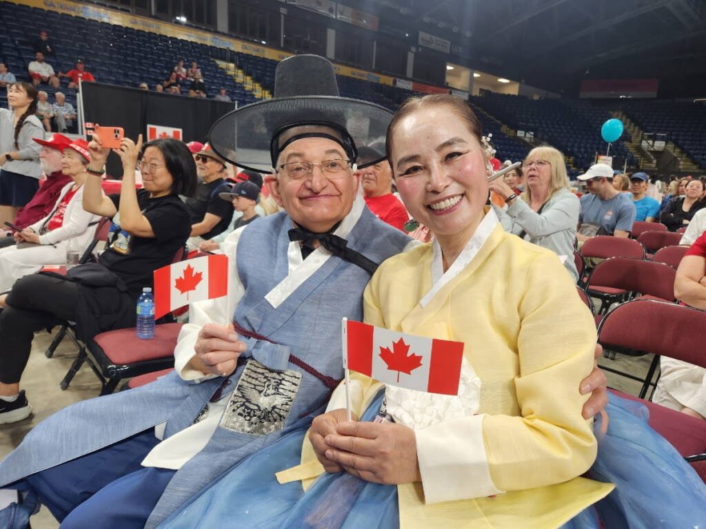 Paul Lauzon and his wife holding Canadian flags at Kelowna Folkfest 2026