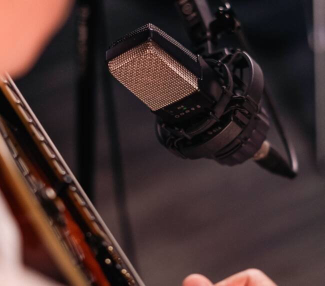 Close-up of an acoustic guitar being recorded with a studio microphone