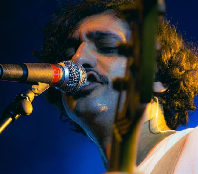 Guitarist singing into a microphone during a live performance