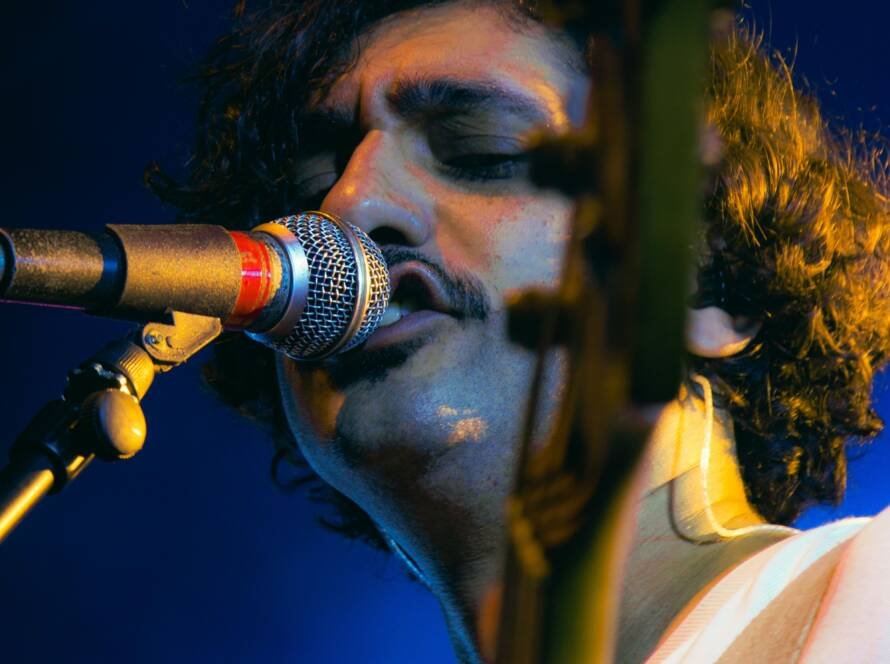 Guitarist singing into a microphone during a live performance