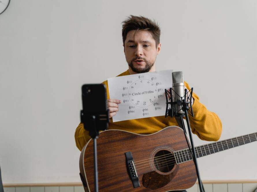 Guitarist reviewing chord structure beside a studio microphone